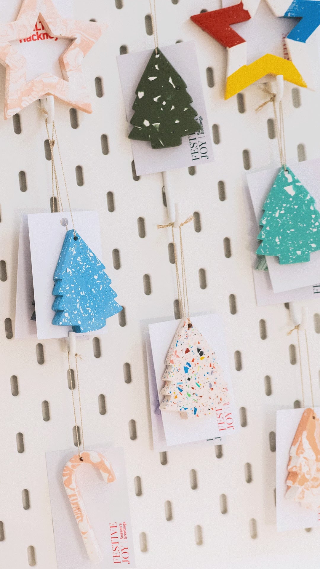 Various shaped Christmas decorations on a white peg board