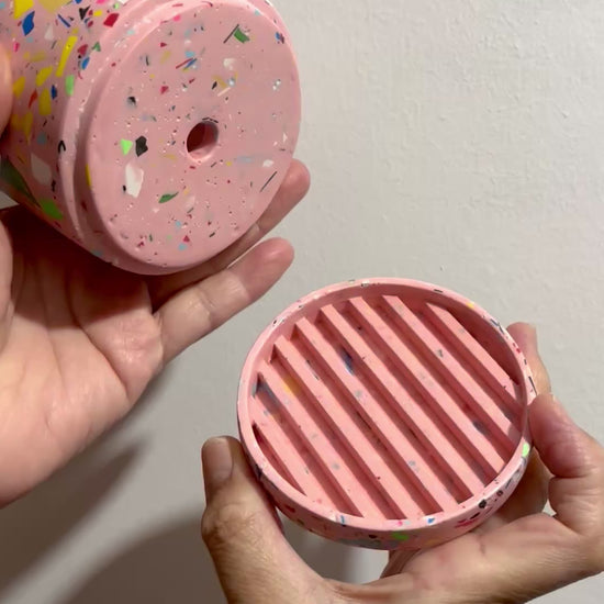 Hands holding the pink based rainbow confetti terrazzo plant pot with drainage hole and a water tray