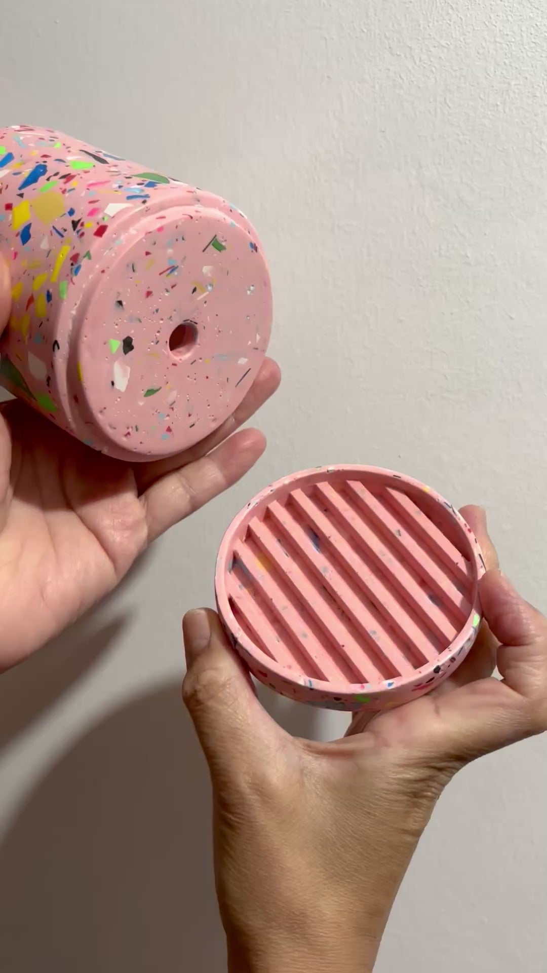 Hands holding the pink based rainbow confetti terrazzo plant pot with drainage hole and a water tray