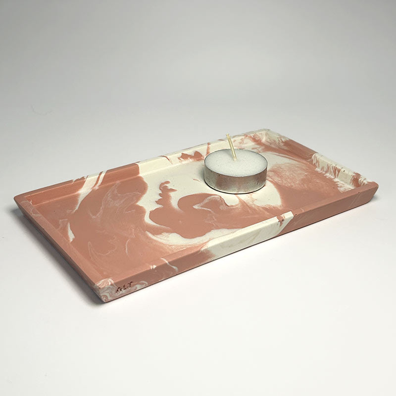 Marble-patterned pink and white tray with a candle on a light gray background