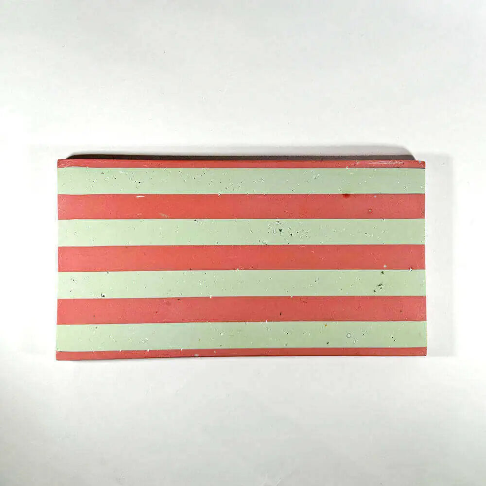 A rectangular tray with horizontal pink and light green stripes, photographed from above on a plain white background.
