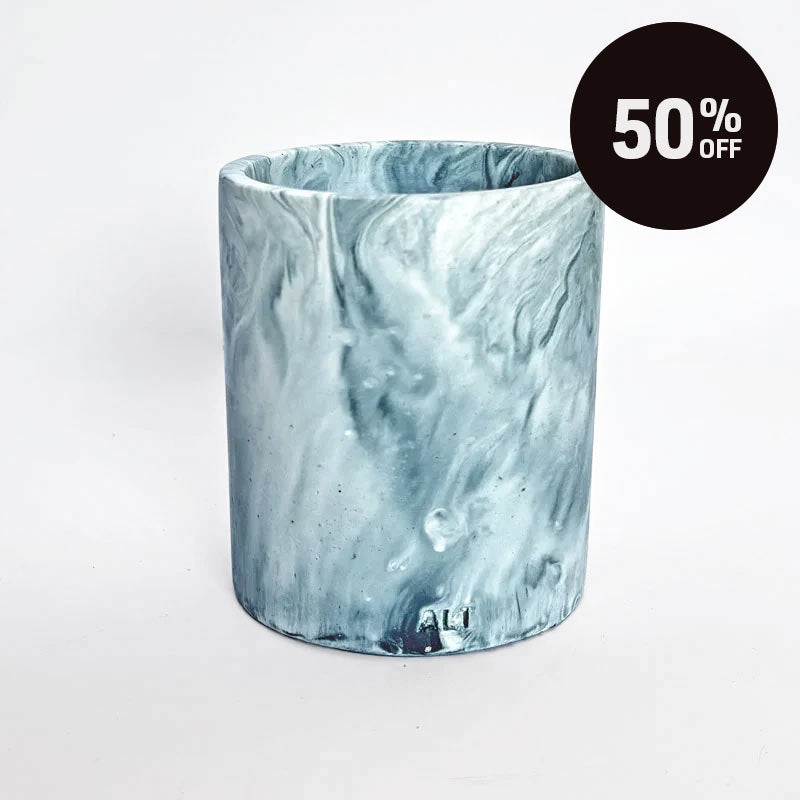 A cylindrical pensil holder with a marble pattern in shades of blue, navy and white, shown on a plain light background with a black '50% OFF' promotional sticker in the top right corner.