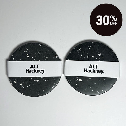 Two round coasters with a black and white terrazzo pattern and a white band across the middle reading 'ALT Hackney.' on a light grey background, with a black circular '30% OFF' badge in the top right corner.