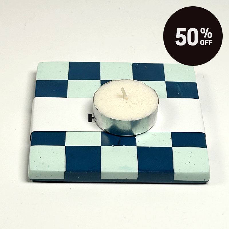 A square coaster with a blue and mint green checkerboard pattern and a white band reading 'ALT Hackney.'  in black text with a tea light on topand a promotional badge with 50% off on top right corner