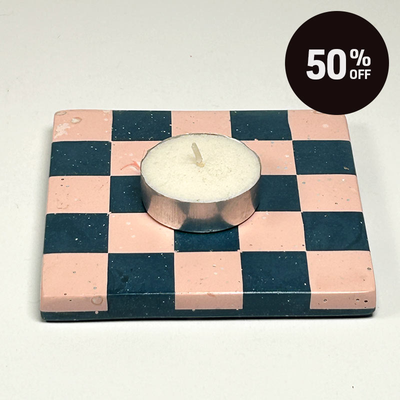 A square coaster with a navy blue and pink checkerboard pattern with a tea light and a promotional badge with 50% off on top right corner
