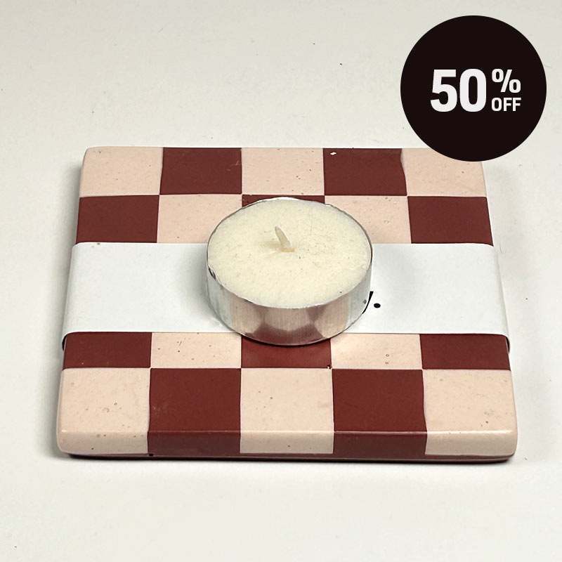 A Dark red and light sand checkerboard patterned coaster, featuring a silver-rimmed white tea light candle on top. A black circular '50% OFF' discount sticker is in the top right corner.