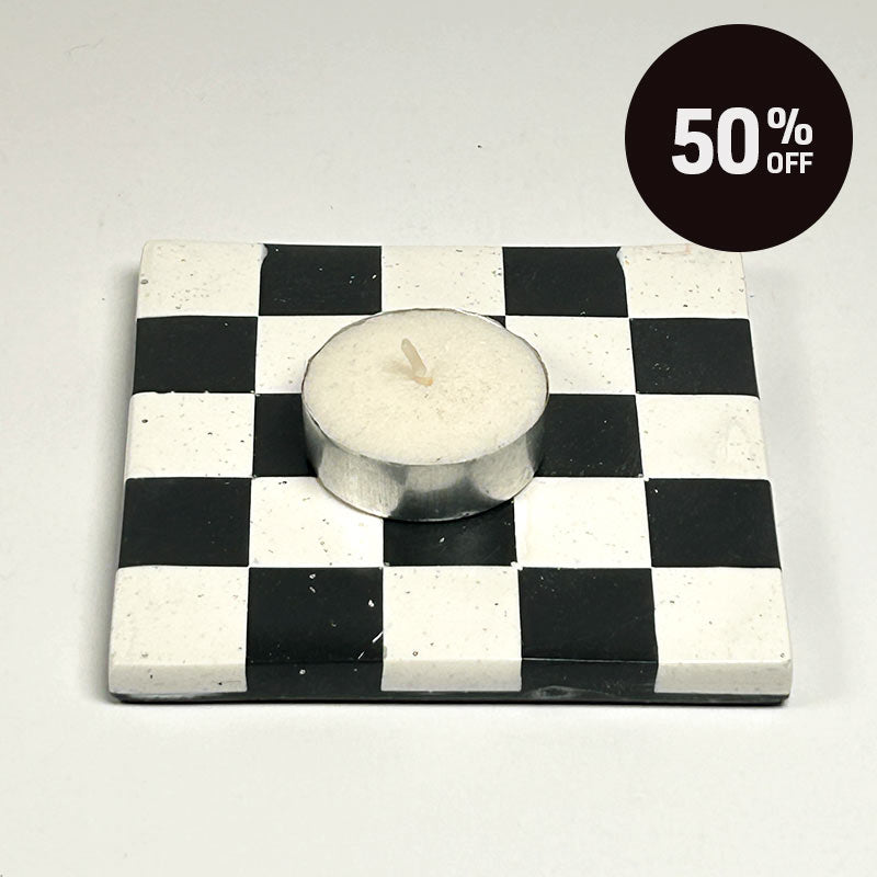 A square coaster with a black and white  checkerboard pattern with a tea light candle  and a promotional badge with 50% off on top right corner