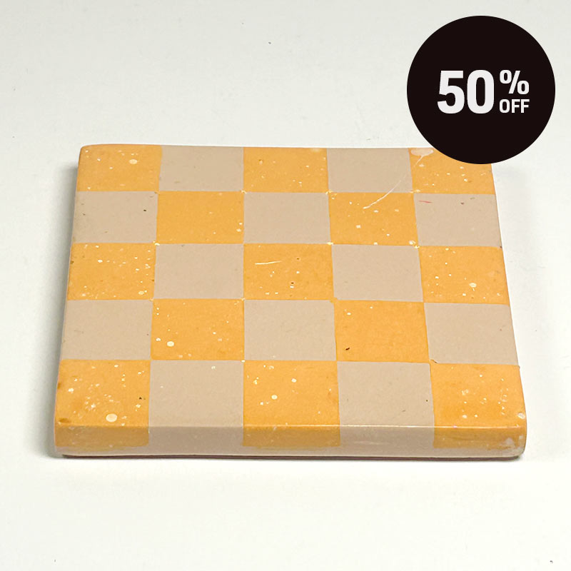 A square coaster with a pastel orange and beige checkerboard pattern and a promotional badge with 50% off on top right corner