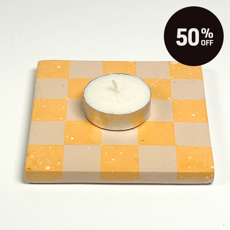 A square coaster with a yellow and beige checkerboard pattern, featuring a white tea light candle in the center. A black circular '50% OFF' discount sticker is in the top right corner.
