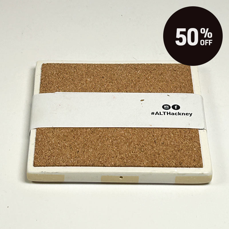 A square cork on a warm beige and white checkerboard patterned coaster on a white background, wrapped in a white paper band labeled 'ALT Hackney.', on a light off-white background with a black '50% OFF' promotional sticker in the top right corner.