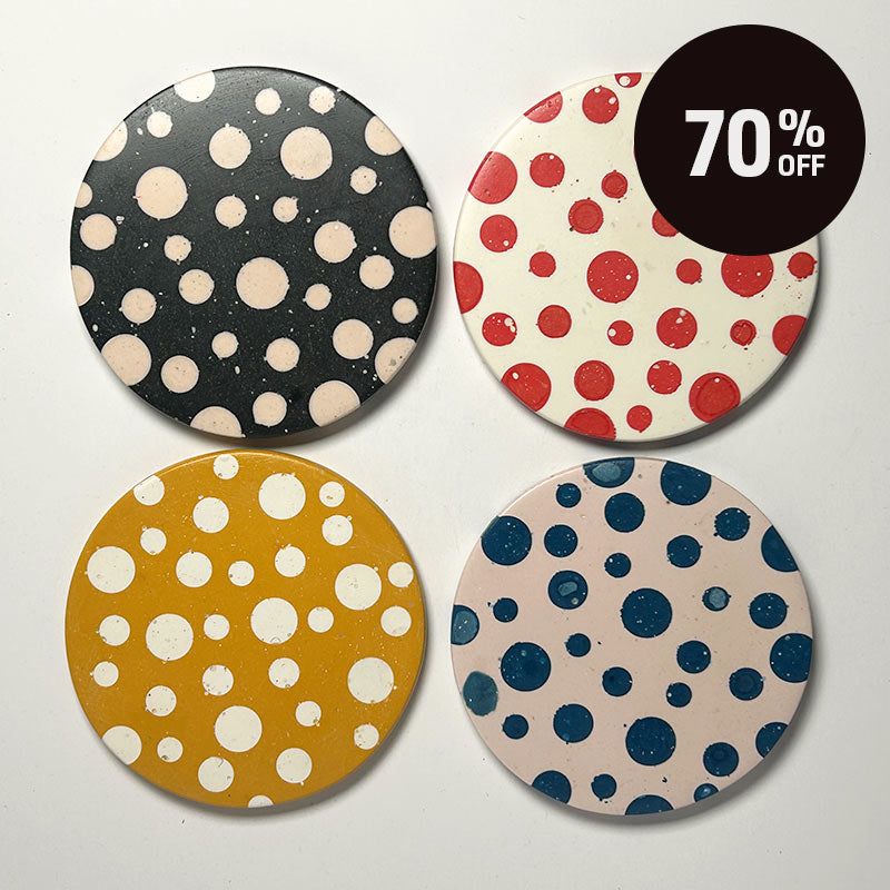 Four round coasters with colorful polka dot patterns arranged in a 2x2 grid on a light background. A black circular sticker overlay in the top right reads '70% OFF'.