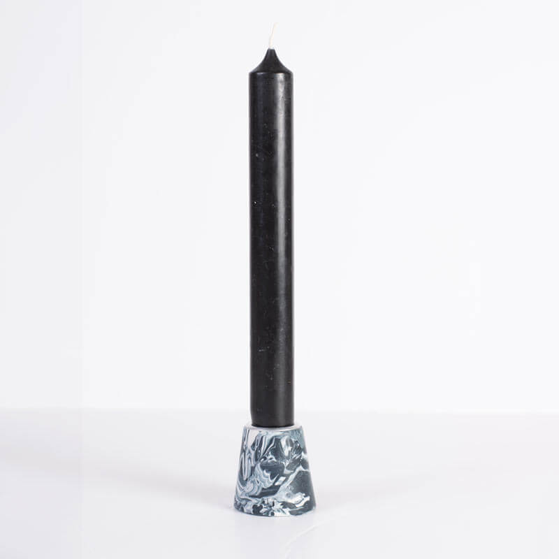 A black taper candle with a marbled Navy and white small taper candle holderwith a silver metal inner rim, shown on a white background