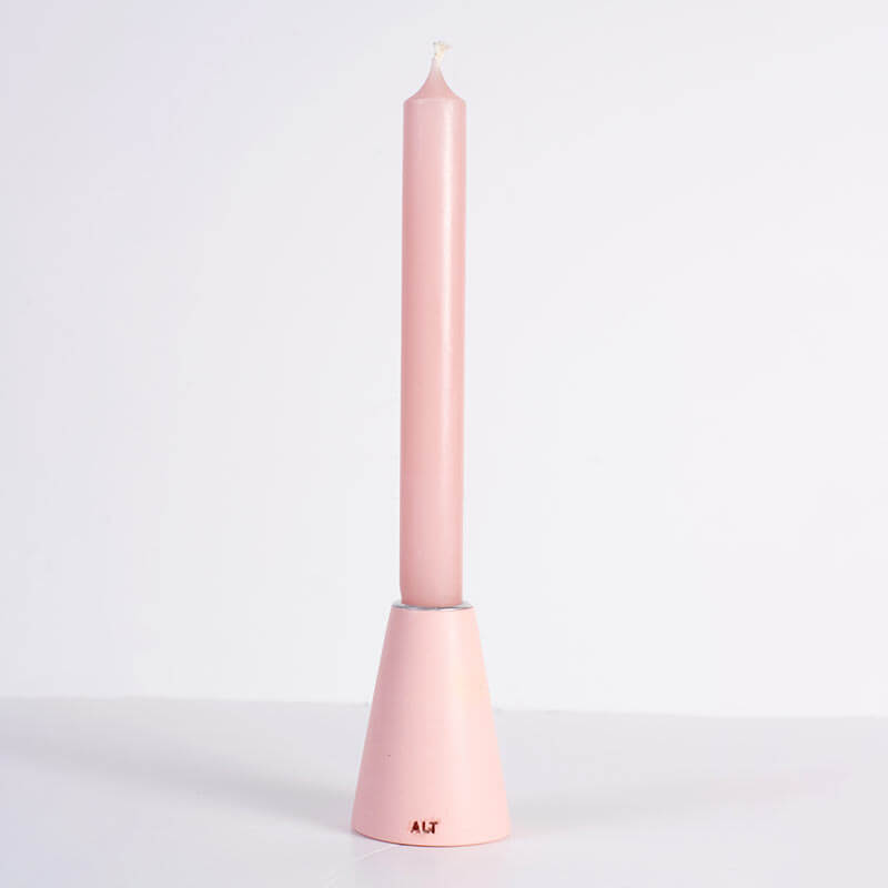 A pink taper candle in a pink taper candle holder with a silver-toned top, shown on a white background