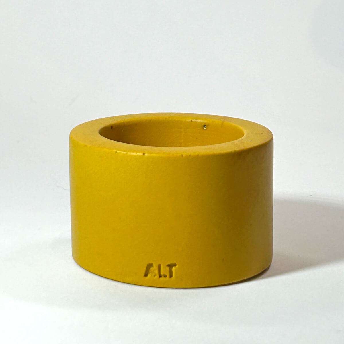 Yellow mustard tea light candle holder with 'A.L.T.' branding on a white background