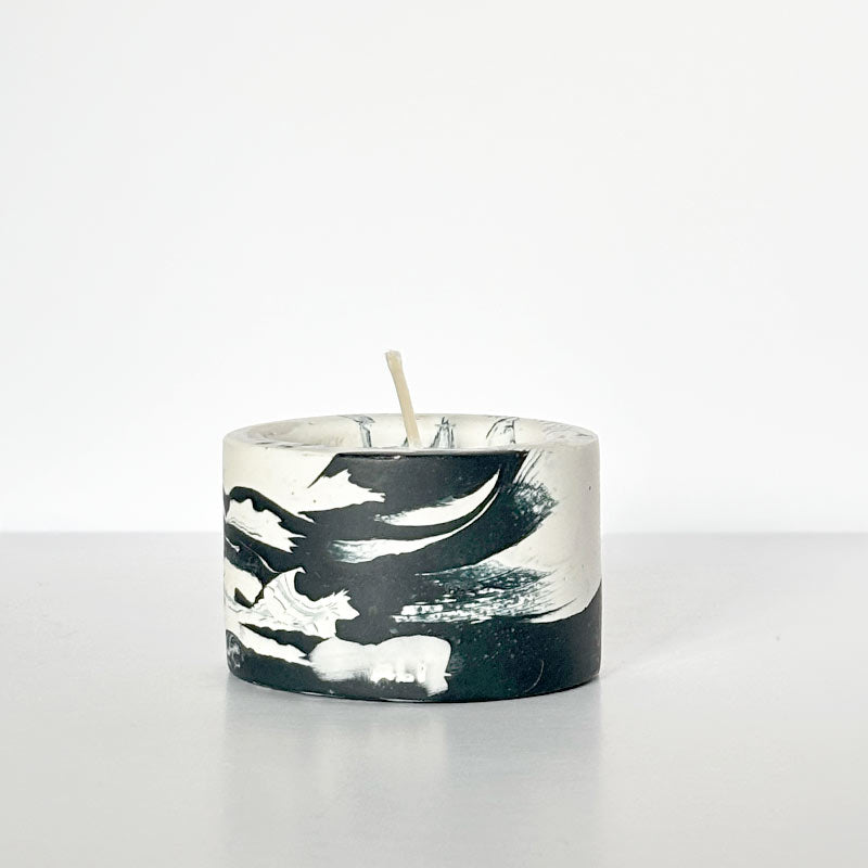 Candle with a marble-patterned navy and white tealight candle holder on a white background