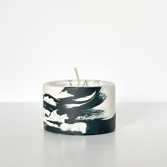 Candle with a marble-patterned navy and white tealight candle holder on a white background