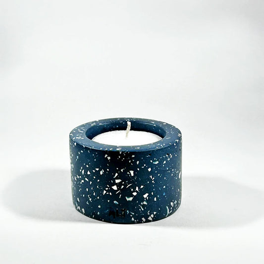 Navy blue terrazzo-patterned tealight candle holder with a white candle inside on a white background