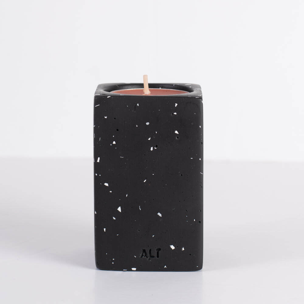 Black speckled candle holder with a candle inside on a white background
