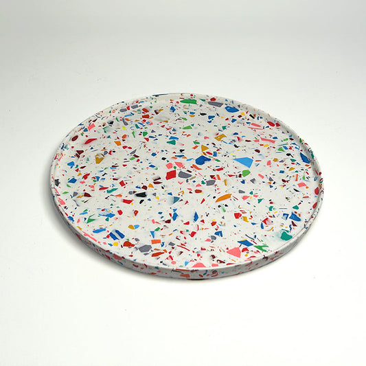 A round tray with a white terrazzo pattern featuring multicolored chips, photographed on a clean white background.