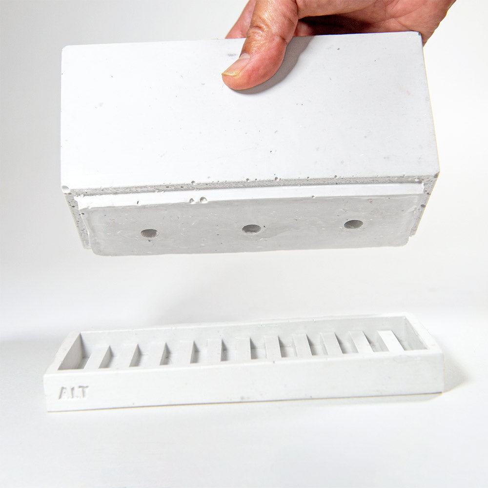 Hand holding a rectangular grey planter with drainage holes and a water tray box with 'ALT' branding on a white background