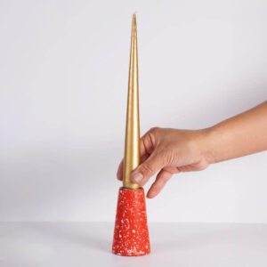 Hand-crafted red with white terrazzo taper candle holder - medium with a hand holding a gold taper candle